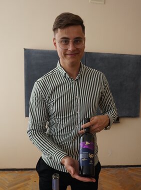 Student holding a wine bottle.